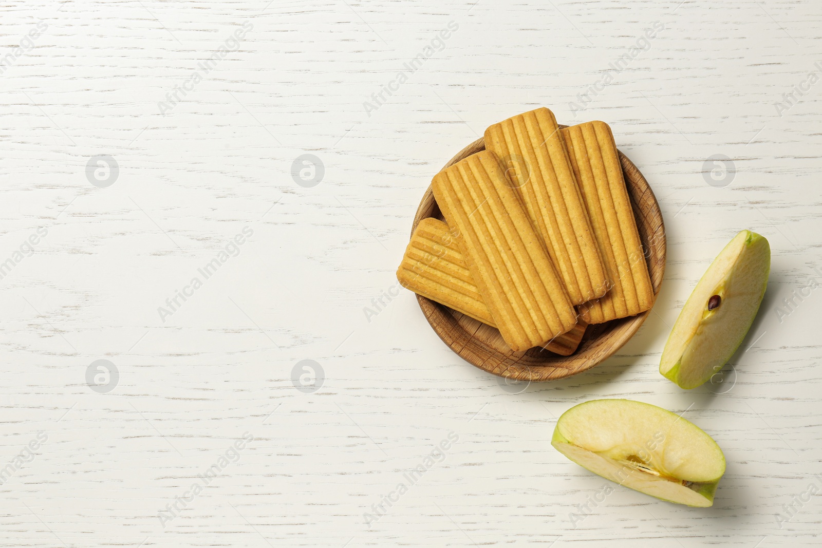 Photo of Cookies and cut apple on white wooden table, flat lay with space for text. Baby finger foods