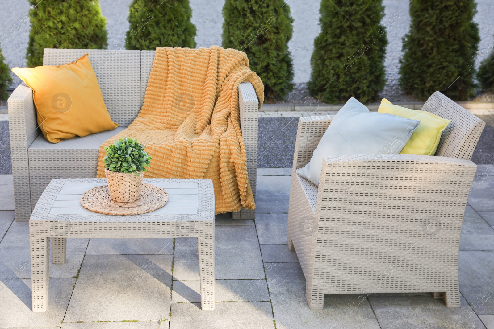 Photo of Beautiful rattan garden furniture, soft pillows, blanket and houseplant outdoors