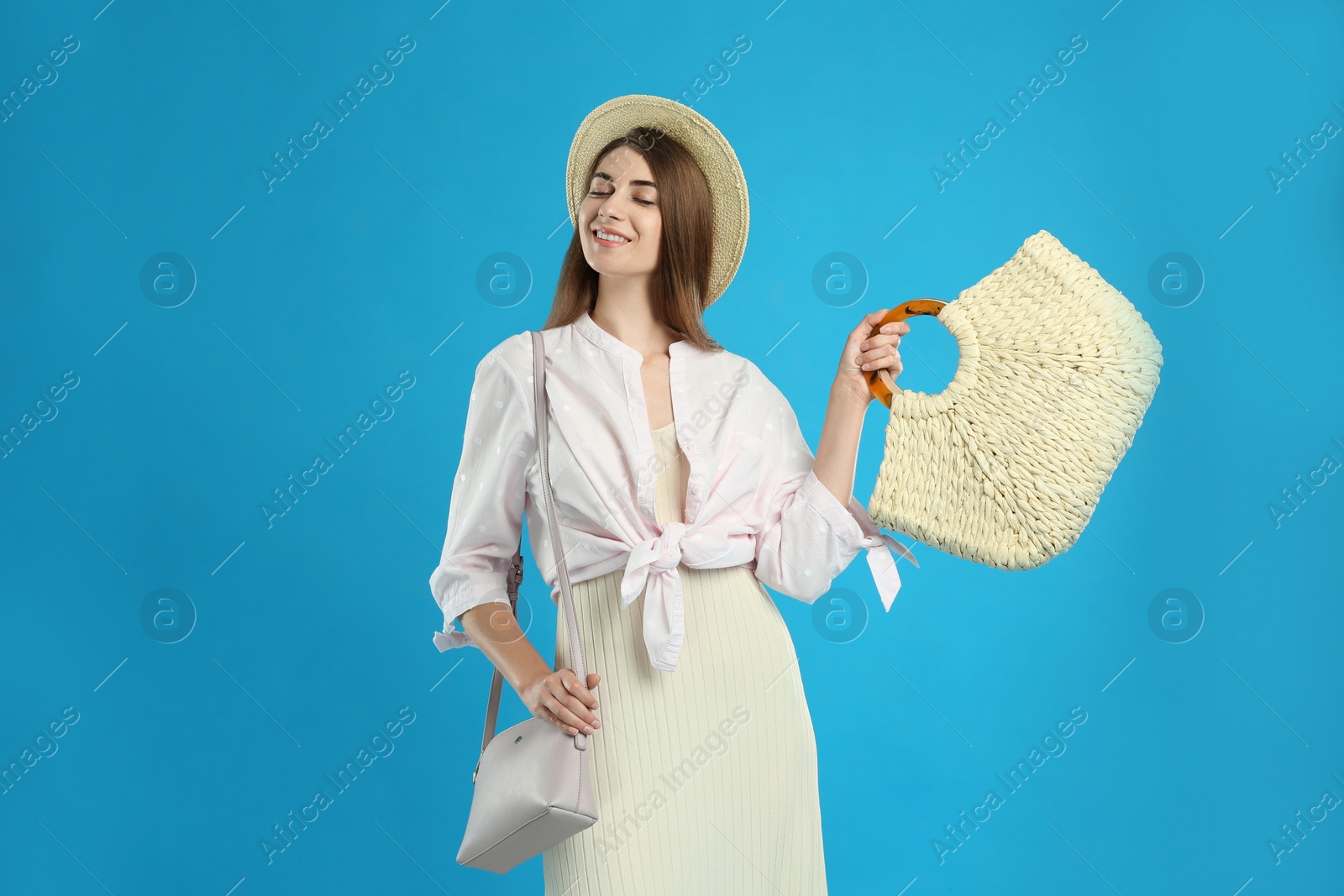 Photo of Beautiful young woman with stylish bags on light blue background