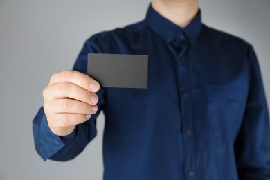 Man holding black business card on grey background, closeup
