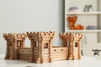Photo of Wooden fortress on white table indoors. Children's toy