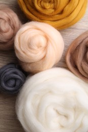 Photo of Colorful felting wool on wooden table, flat lay