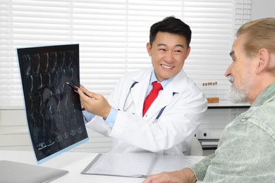 Happy doctor showing MRI images to senior patient in hospital