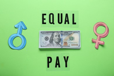 Photo of Equal pay. Gender symbols with stack of dollar banknotes on green background, flat lay