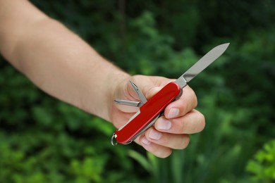 Photo of Man holding compact portable multitool outdoors, closeup