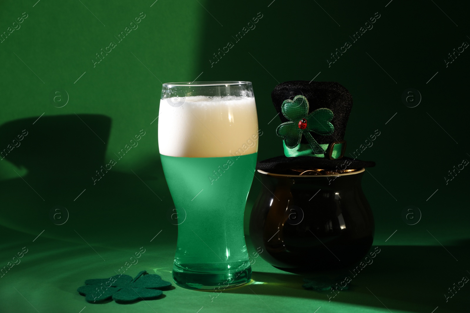 Photo of St. Patrick's day party. Green beer, leprechaun hat, pot of gold and decorative clover leaves on green background