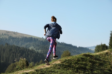 Young woman running on mountain trail in summer