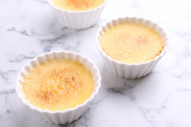 Delicious creme brulee in bowls on white marble table, closeup