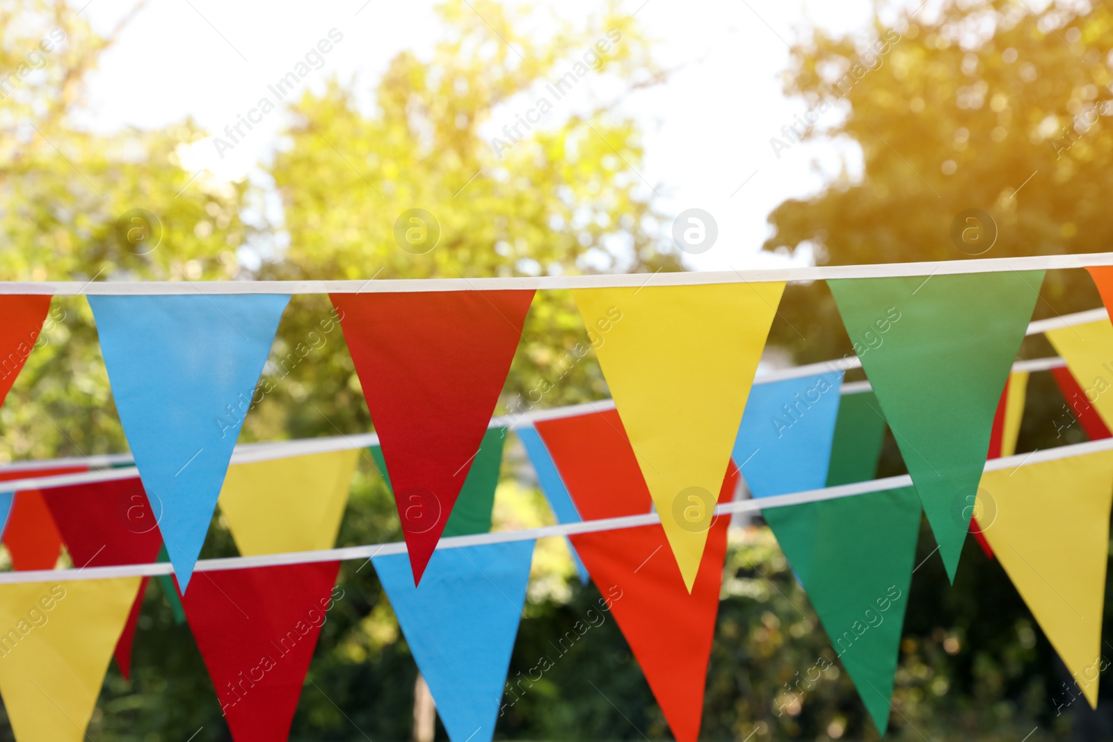 Photo of Colorful bunting flags in park. Party decor