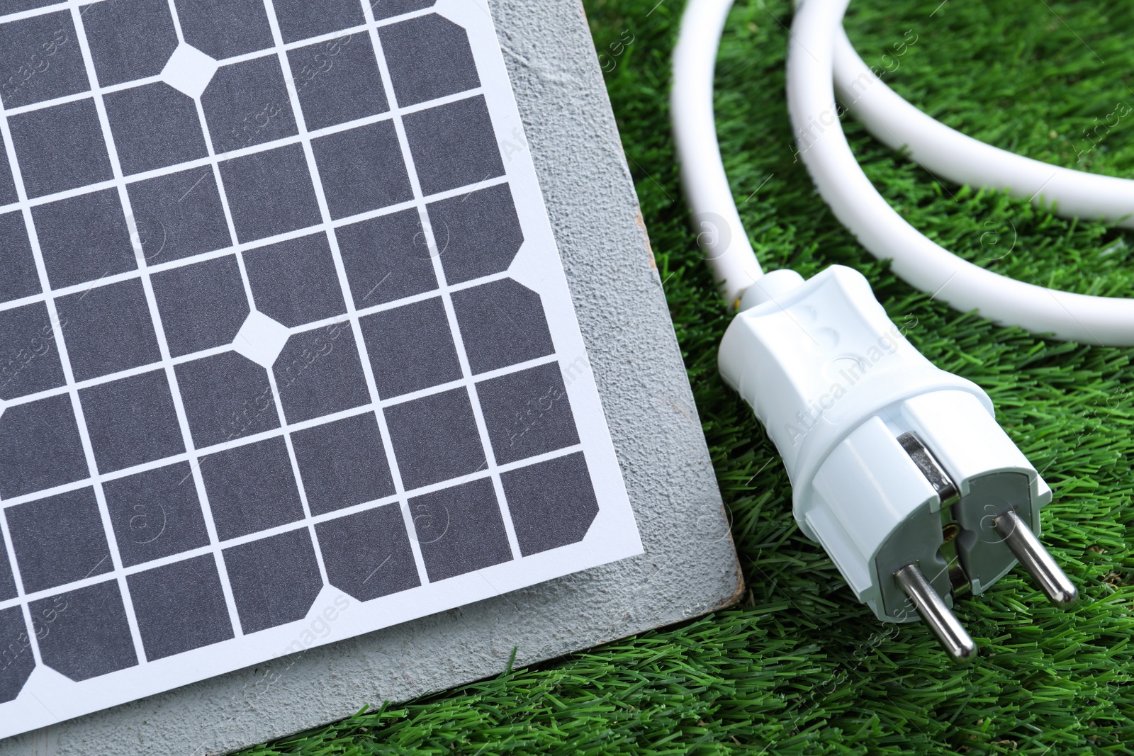 Photo of Solar panel and cable on green grass, closeup