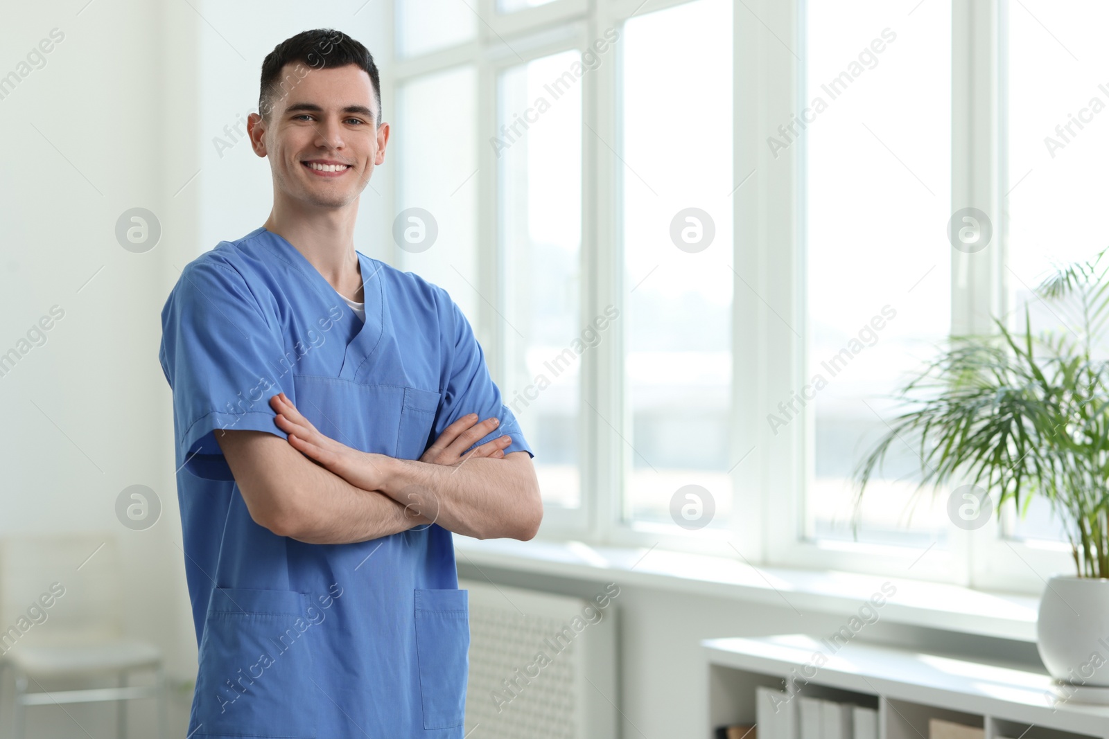 Photo of Portrait of smiling medical assistant with crossed arms in hospital. Space for text