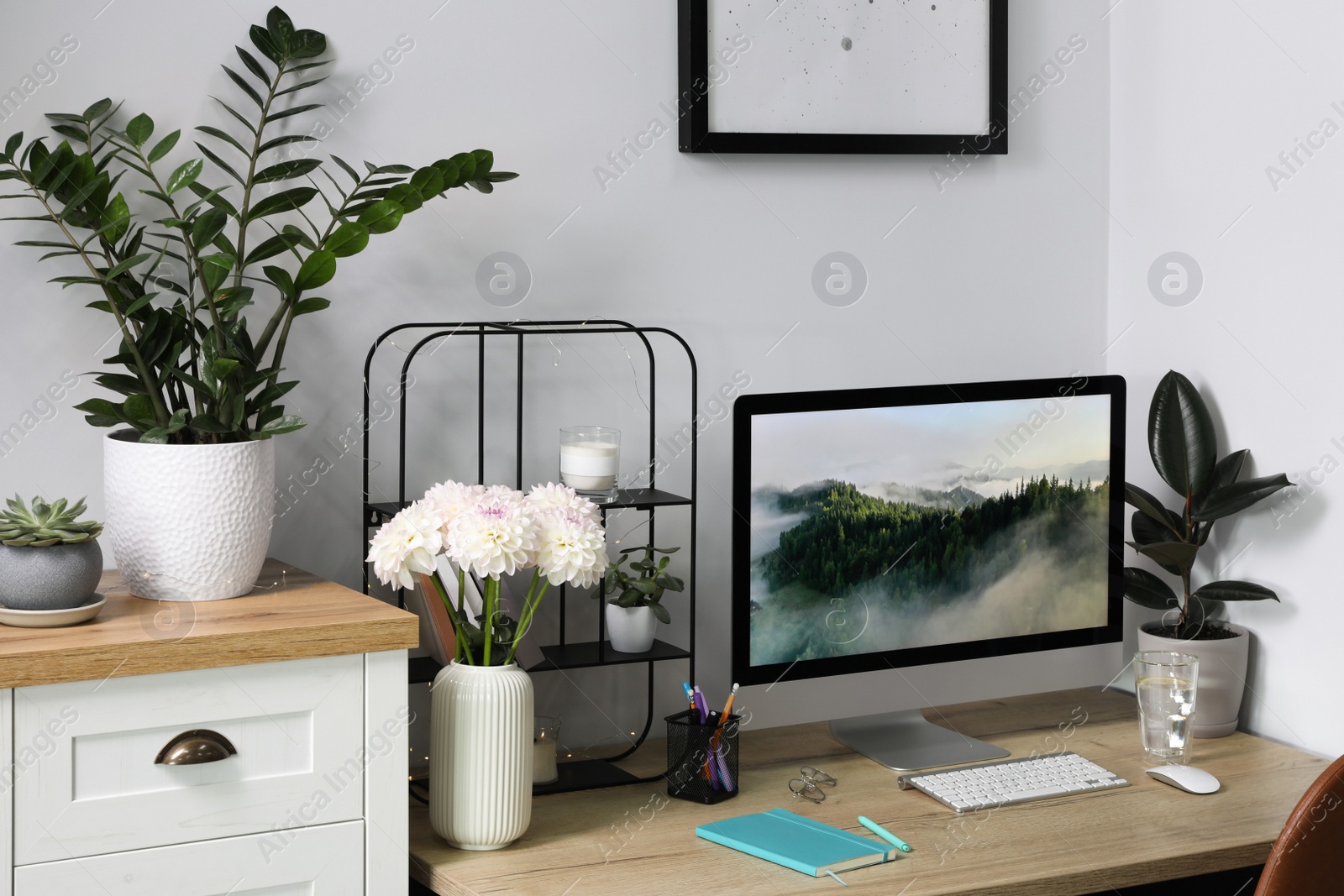 Photo of Comfortable workplace with modern computer, decor and office supplies on wooden table indoors