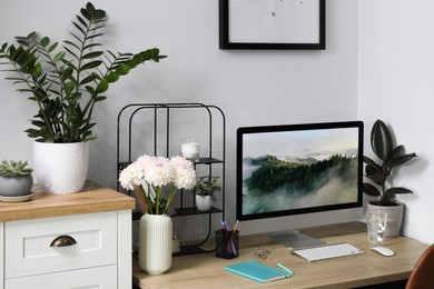 Comfortable workplace with modern computer, decor and office supplies on wooden table indoors