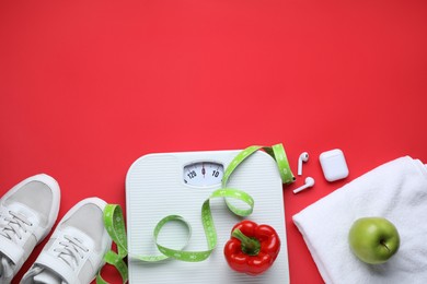 Flat lay composition with scales and measuring tape on red background, space for text