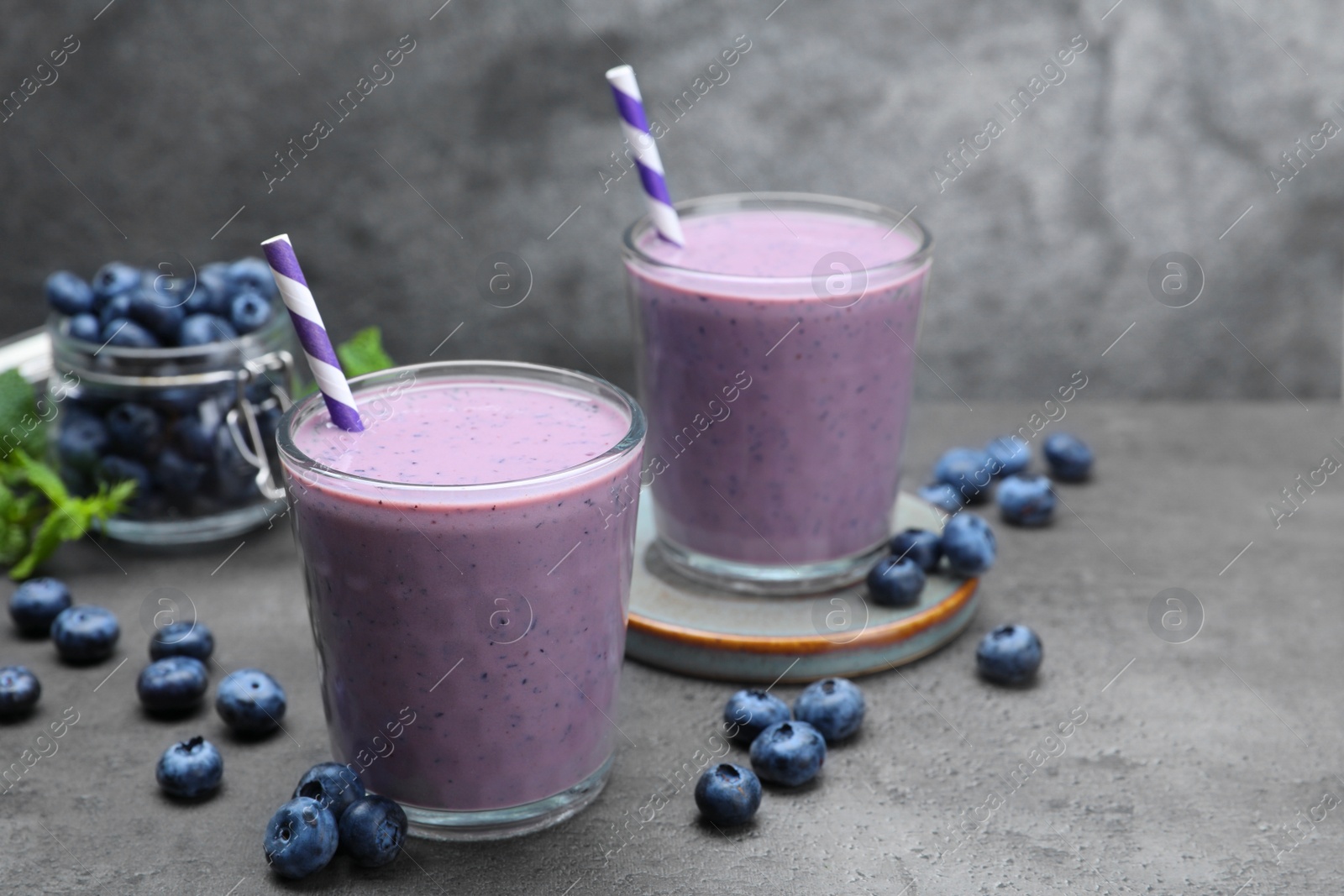 Photo of Tasty blueberry smoothie with fresh berries on grey table. Space for text