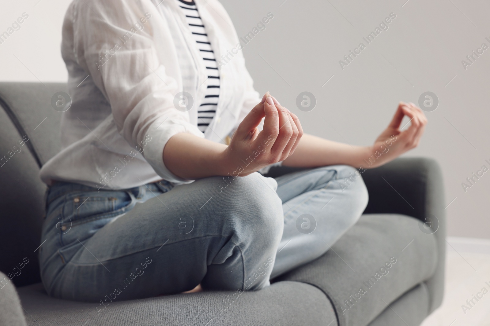 Photo of Woman meditating on sofa indoors, closeup. Harmony and zen