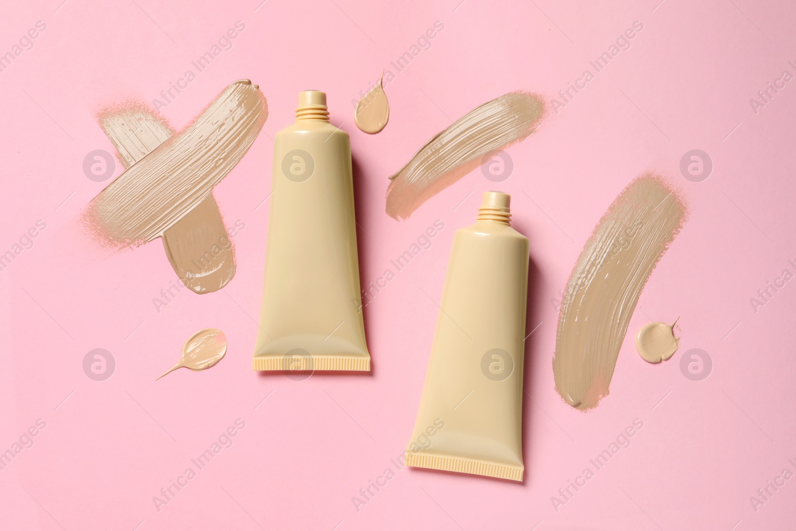 Photo of Liquid foundations and swatches on pink background, flat lay
