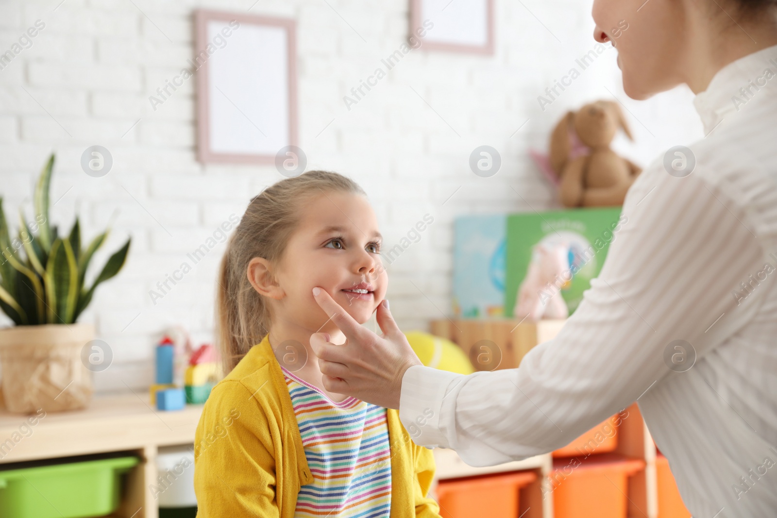 Photo of Speech therapist working with little girl in office