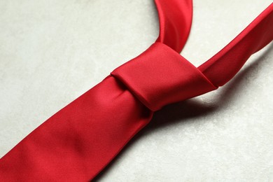 Photo of One red necktie on light textured table, closeup
