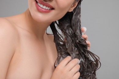 Photo of Smiling woman washing hair on grey background, closeup