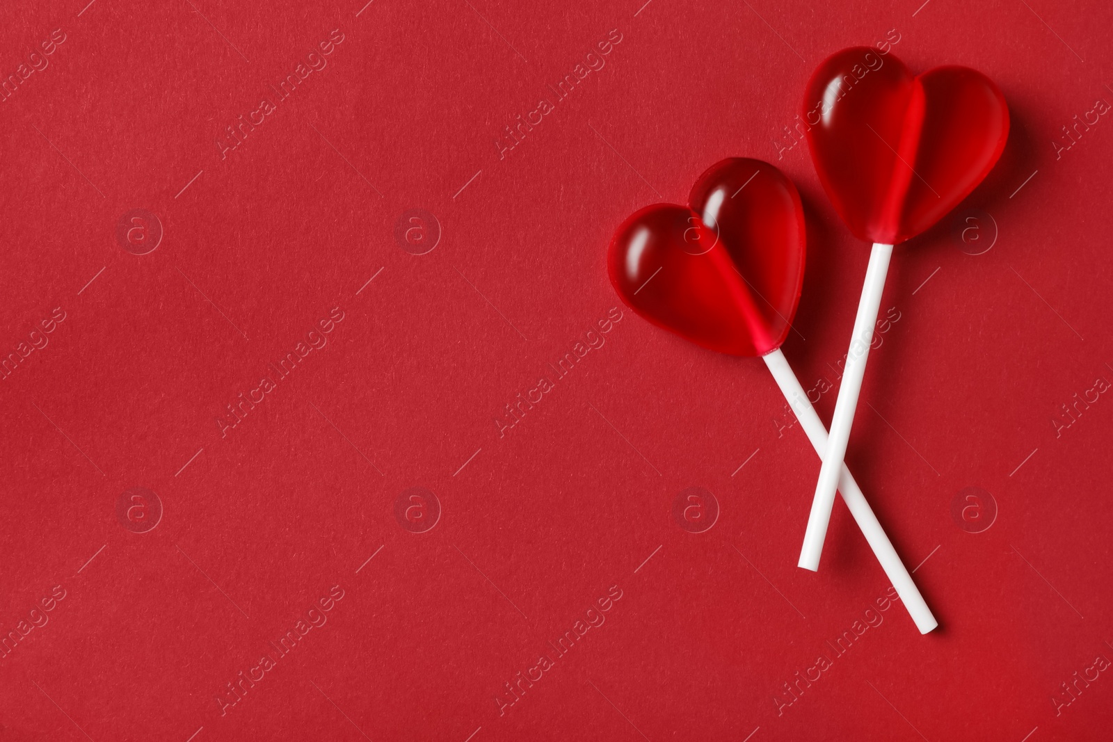 Photo of Sweet heart shaped lollipops on red background, flat lay with space for text. Valentine's day celebration