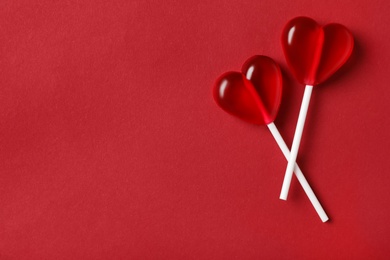 Sweet heart shaped lollipops on red background, flat lay with space for text. Valentine's day celebration