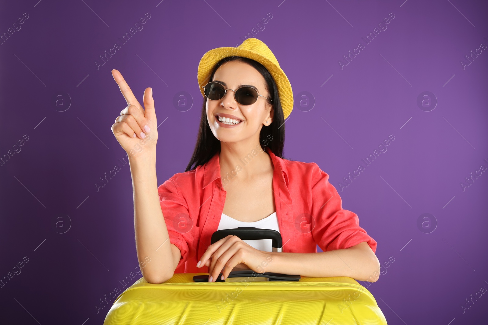Photo of Beautiful woman with suitcase for summer trip on purple background. Vacation travel