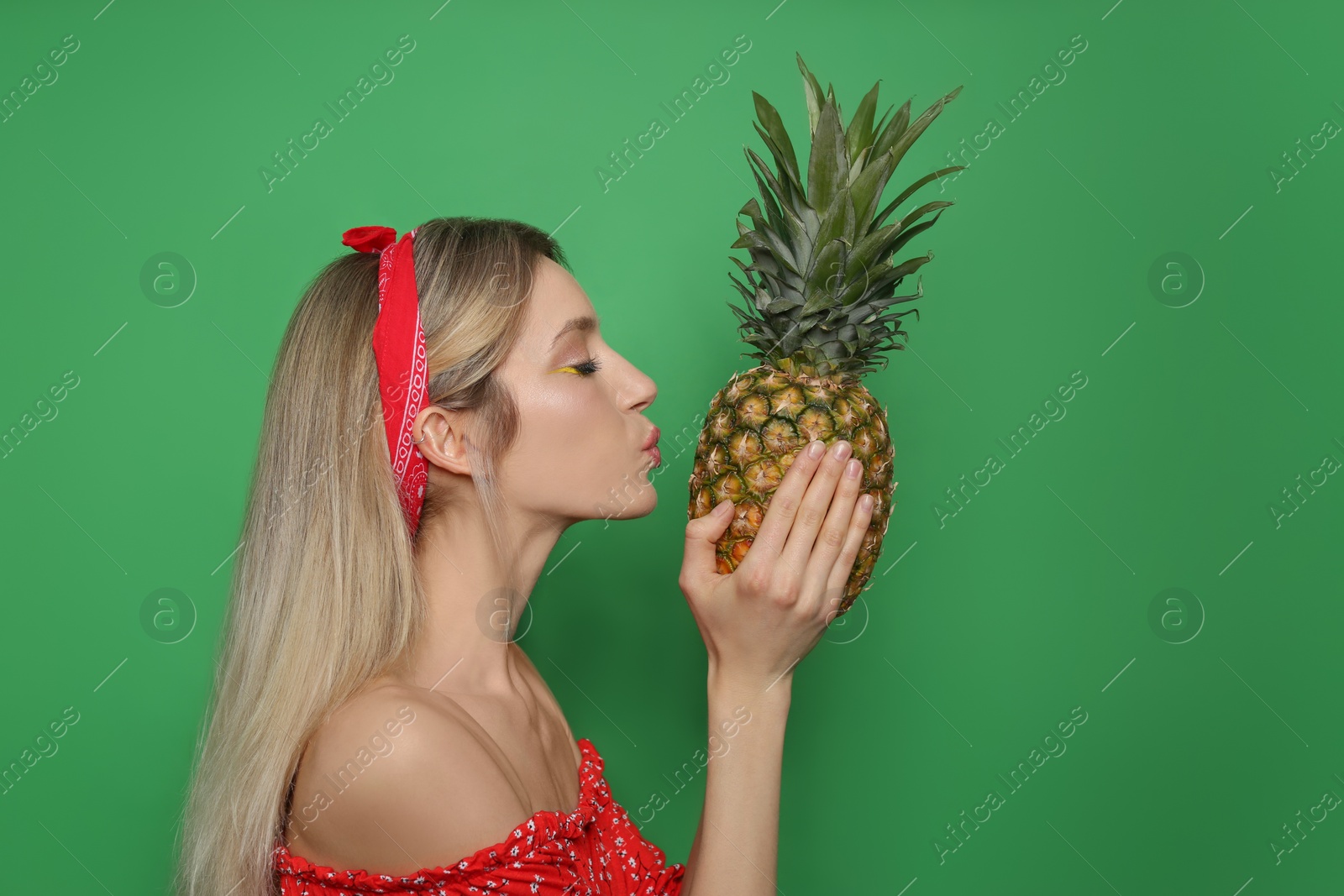 Photo of Young woman with fresh pineapple on green background. Exotic fruit