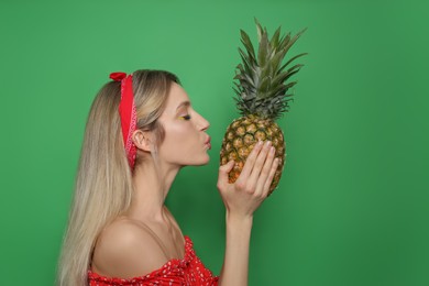 Photo of Young woman with fresh pineapple on green background. Exotic fruit