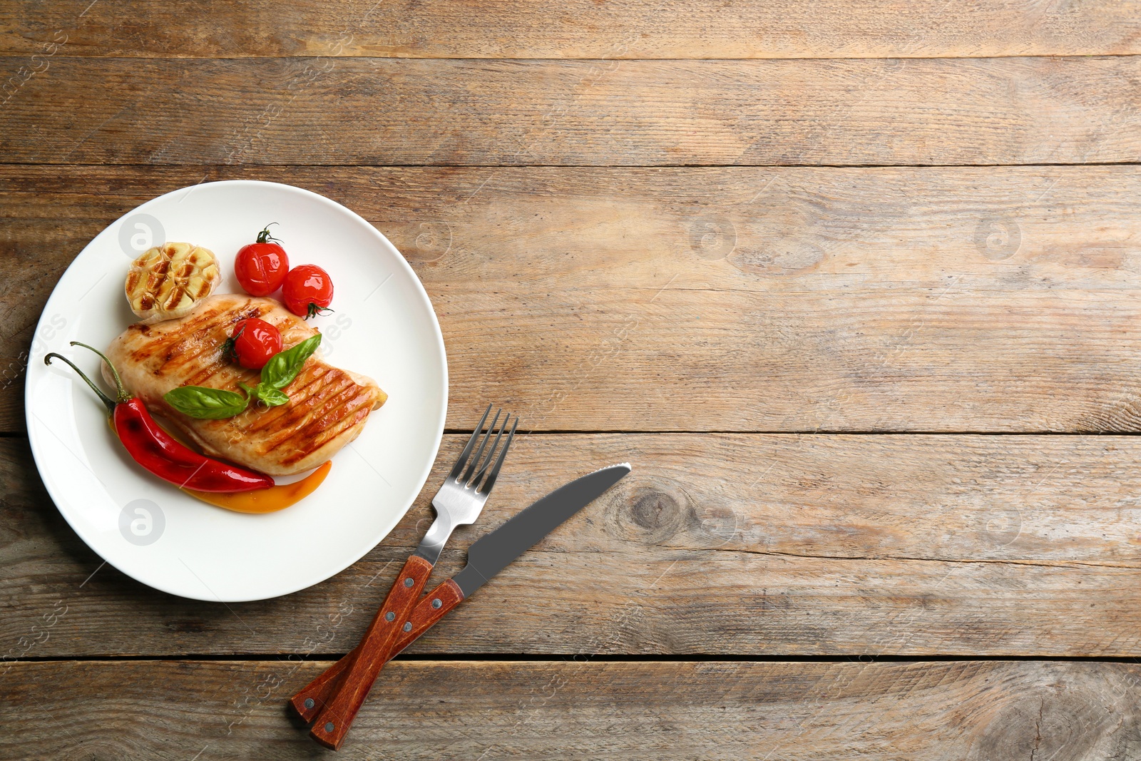 Photo of Tasty grilled chicken fillets with vegetables served on wooden table, flat lay. Space for text