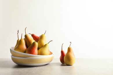 Plate with ripe pears on table against light background. Space for text