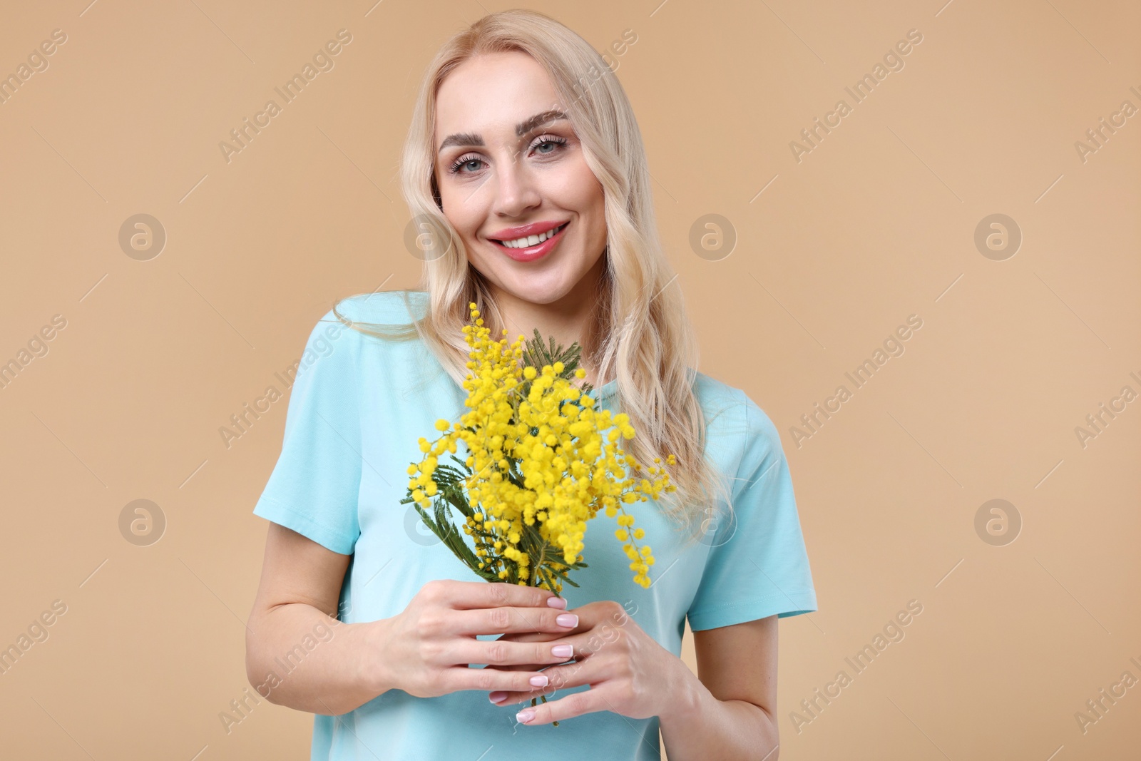 Photo of Happy young woman with beautiful bouquet on beige background