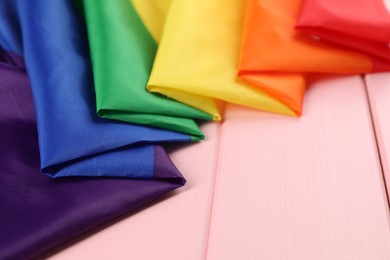 Photo of Rainbow LGBT flag on pink wooden table. Space for text