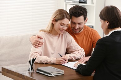 Photo of Professional notary helping couple with paperwork in office