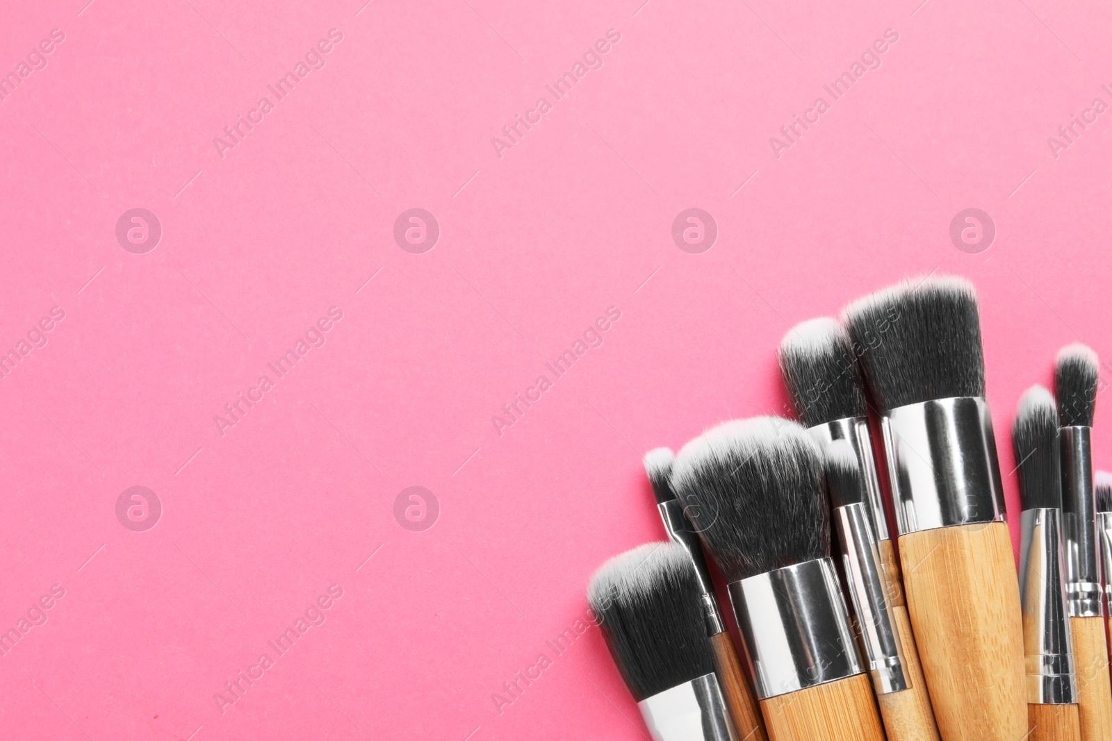 Photo of Set of makeup brushes on pink background, flat lay. Space for text