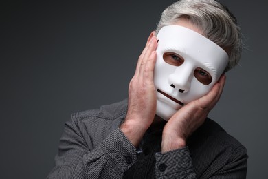 Photo of Multiple personality concept. Man in mask on dark grey background, space for text