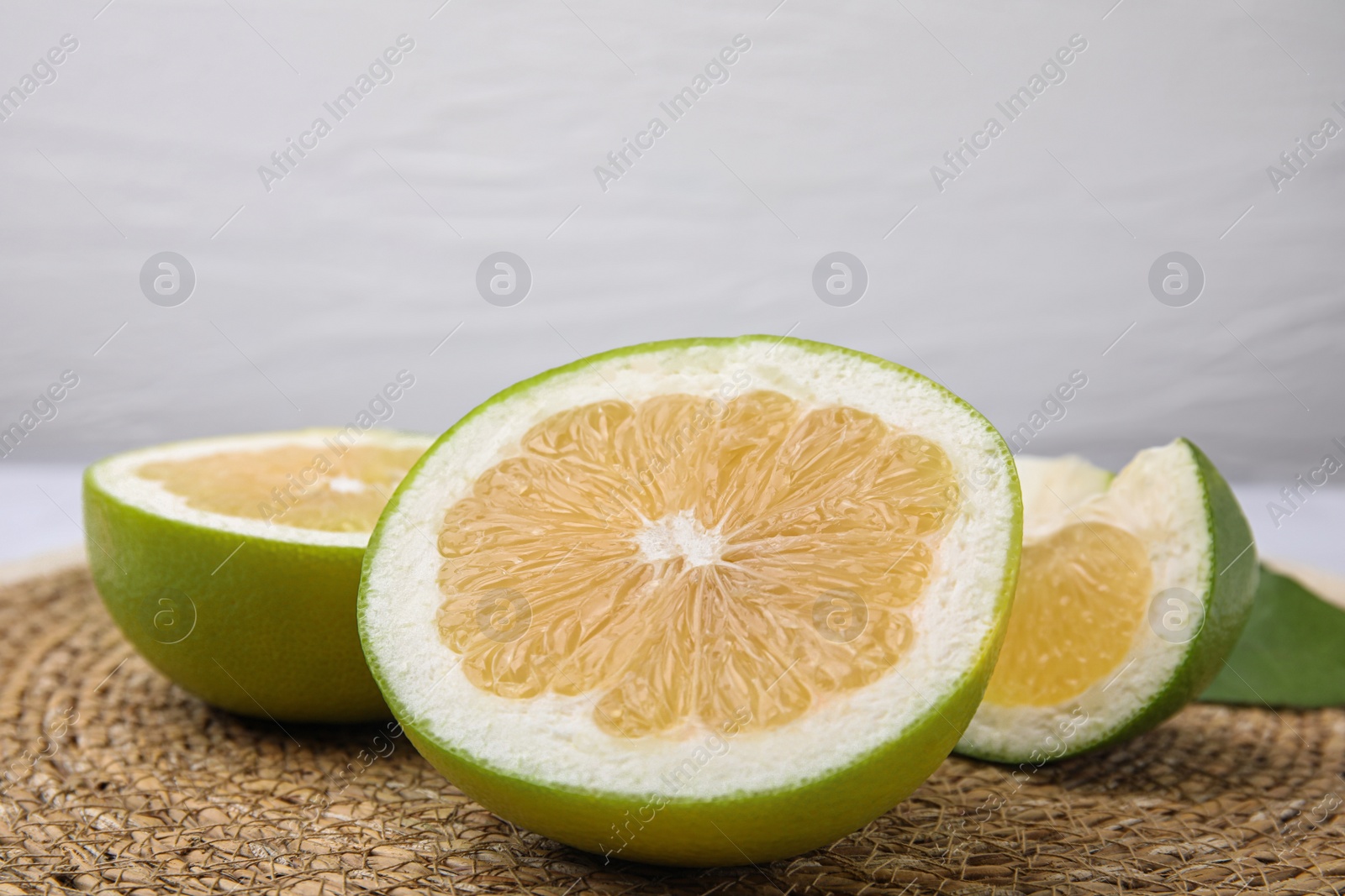 Photo of Cut sweetie fruits on wicker mat, closeup