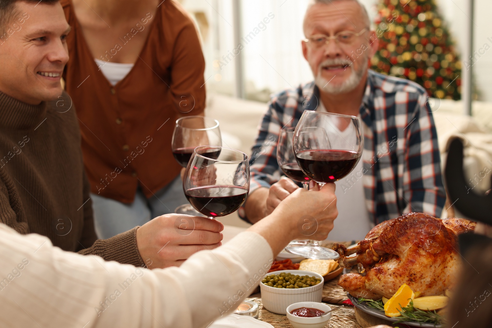 Photo of Family clinking glasses of wine at festive dinner, focus on hands. Christmas celebration