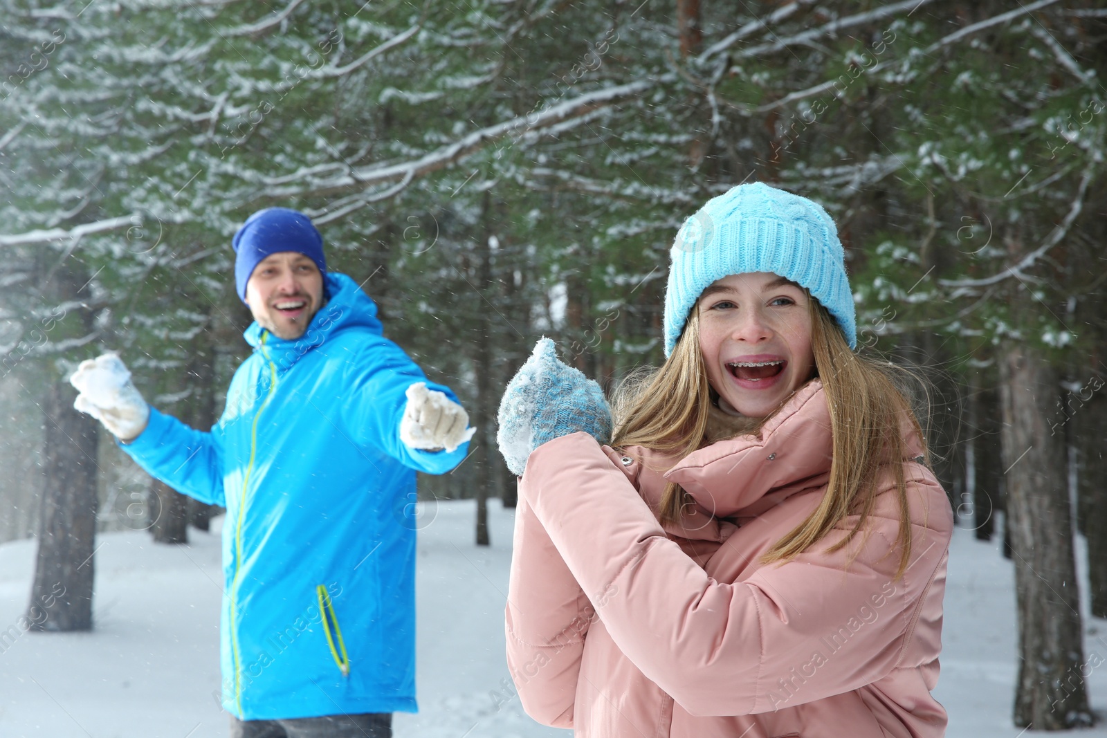 Photo of Happy father and daughter playing snowballs in winter forest