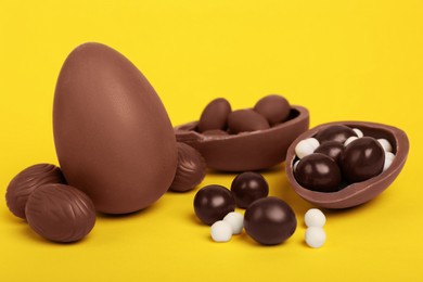 Photo of Delicious chocolate eggs and candies on yellow background, closeup