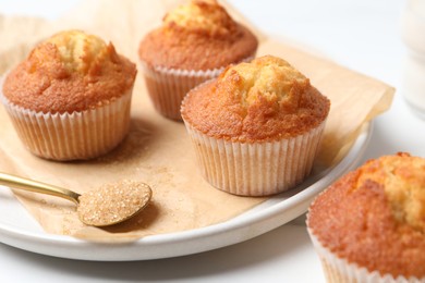 Delicious sweet muffins and brown sugar on white table, closeup