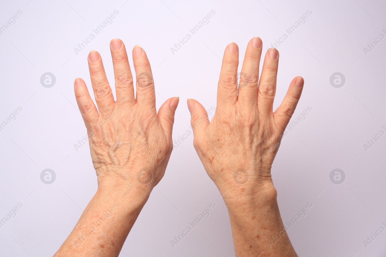 Photo of Closeup view of older woman's hands on white background