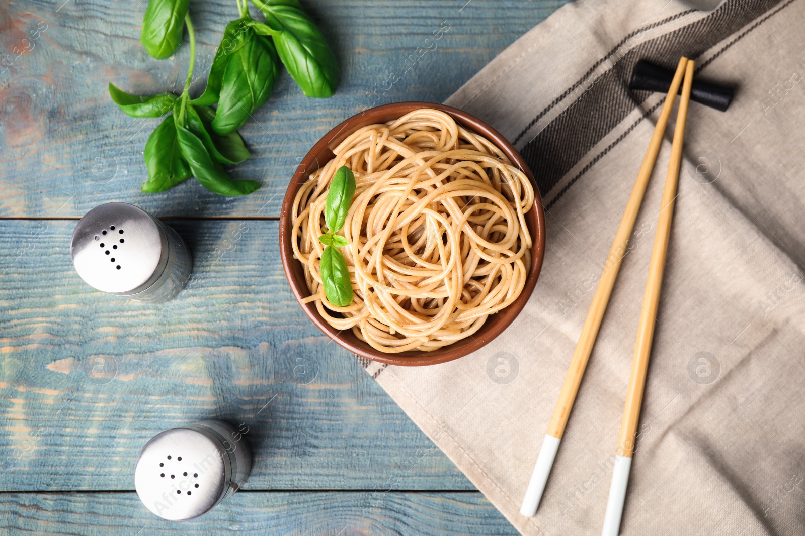 Photo of Tasty buckwheat noodles served on blue wooden table, flat lay