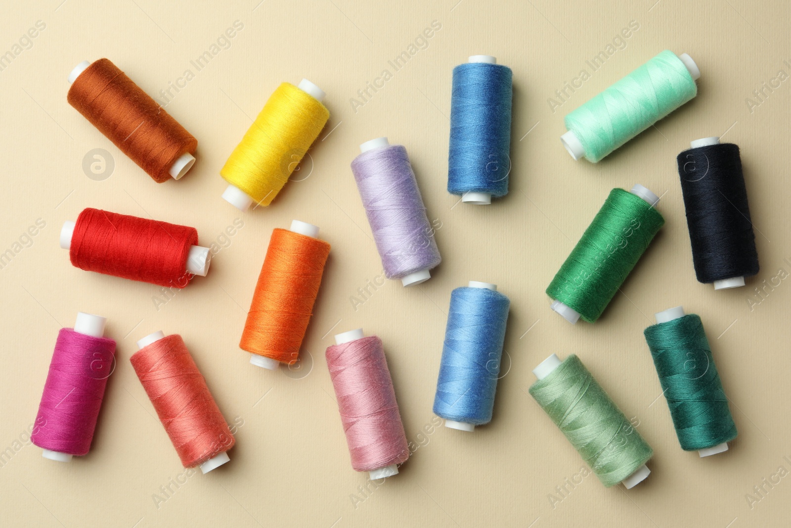 Photo of Flat lay composition with colorful sewing threads on beige background