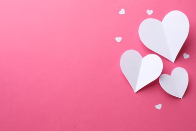 Photo of White paper hearts on pink background, flat lay. Space for text