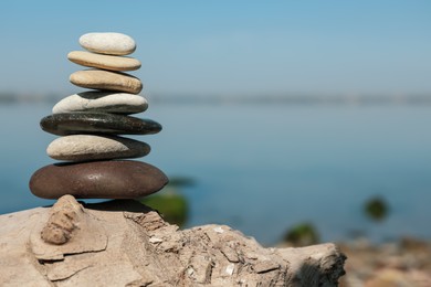 Stack of stones on rock near river, space for text. Harmony and balance concept