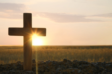 Photo of Wooden Christian cross outdoors at sunrise, space for text. Religion concept