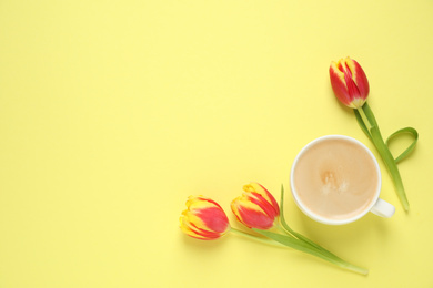 Photo of Cup of morning coffee and tulips on yellow background, flat lay. Space for text
