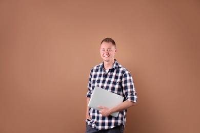 Portrait of handsome man with laptop on color background