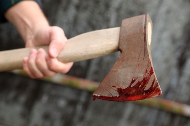 Photo of Man holding bloody axe outdoors, closeup view